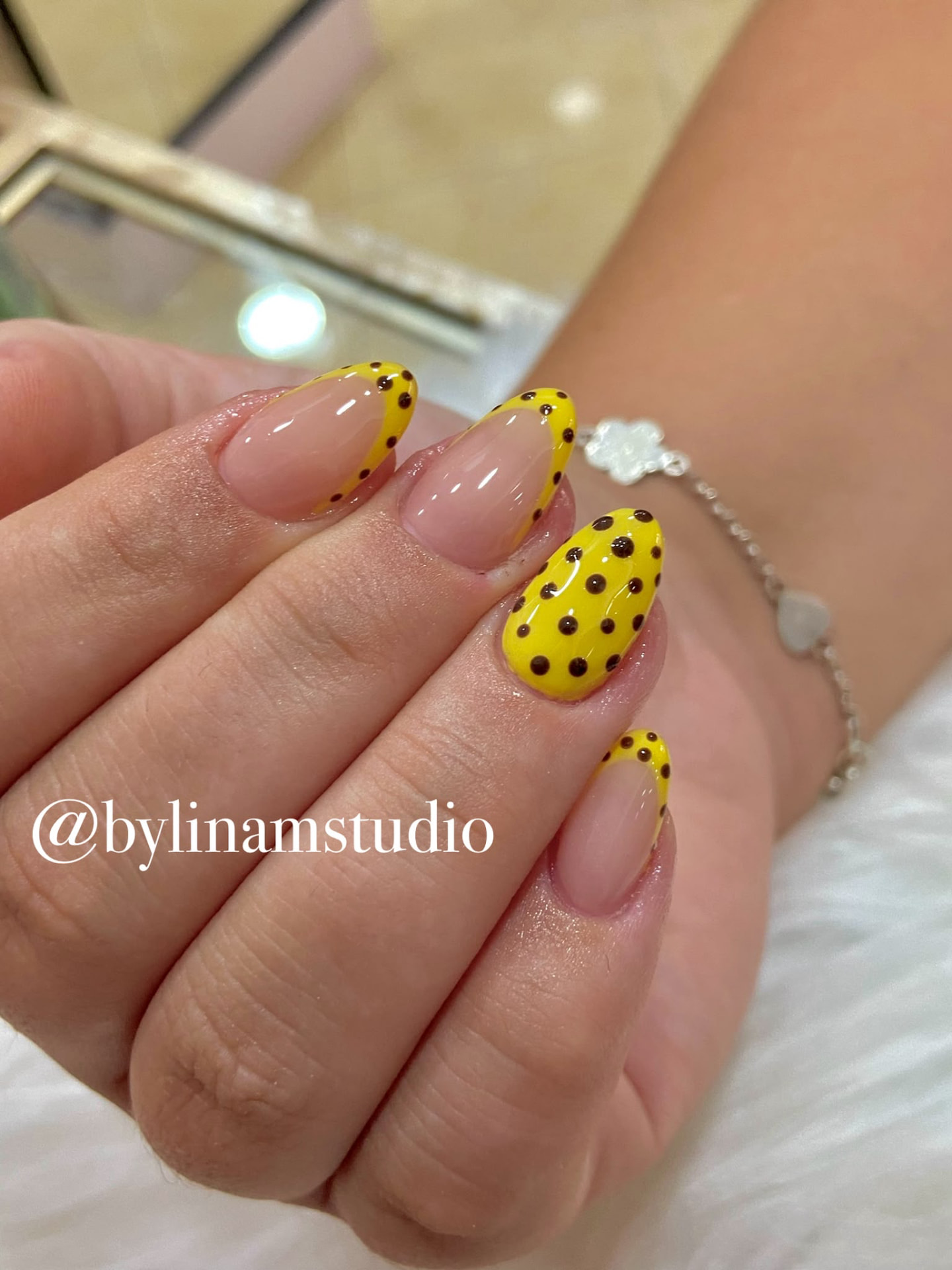 Manicura almendrada nude con francesa amarilla y lunares negros