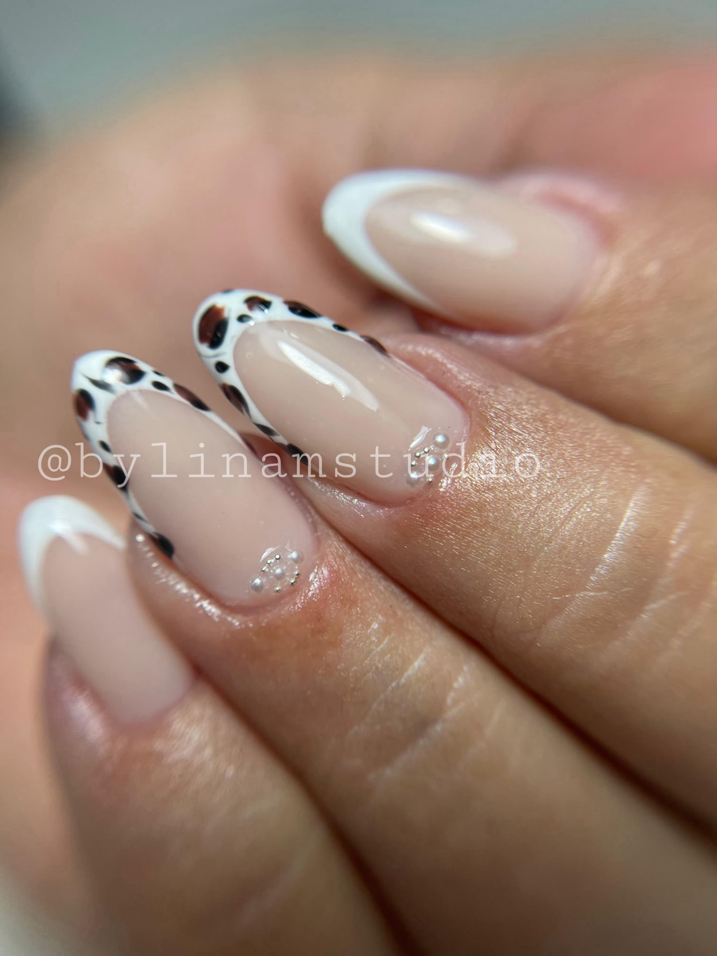 Manicura almendrada nude con francesa blanca, estampado animal y perlas en la cutícula