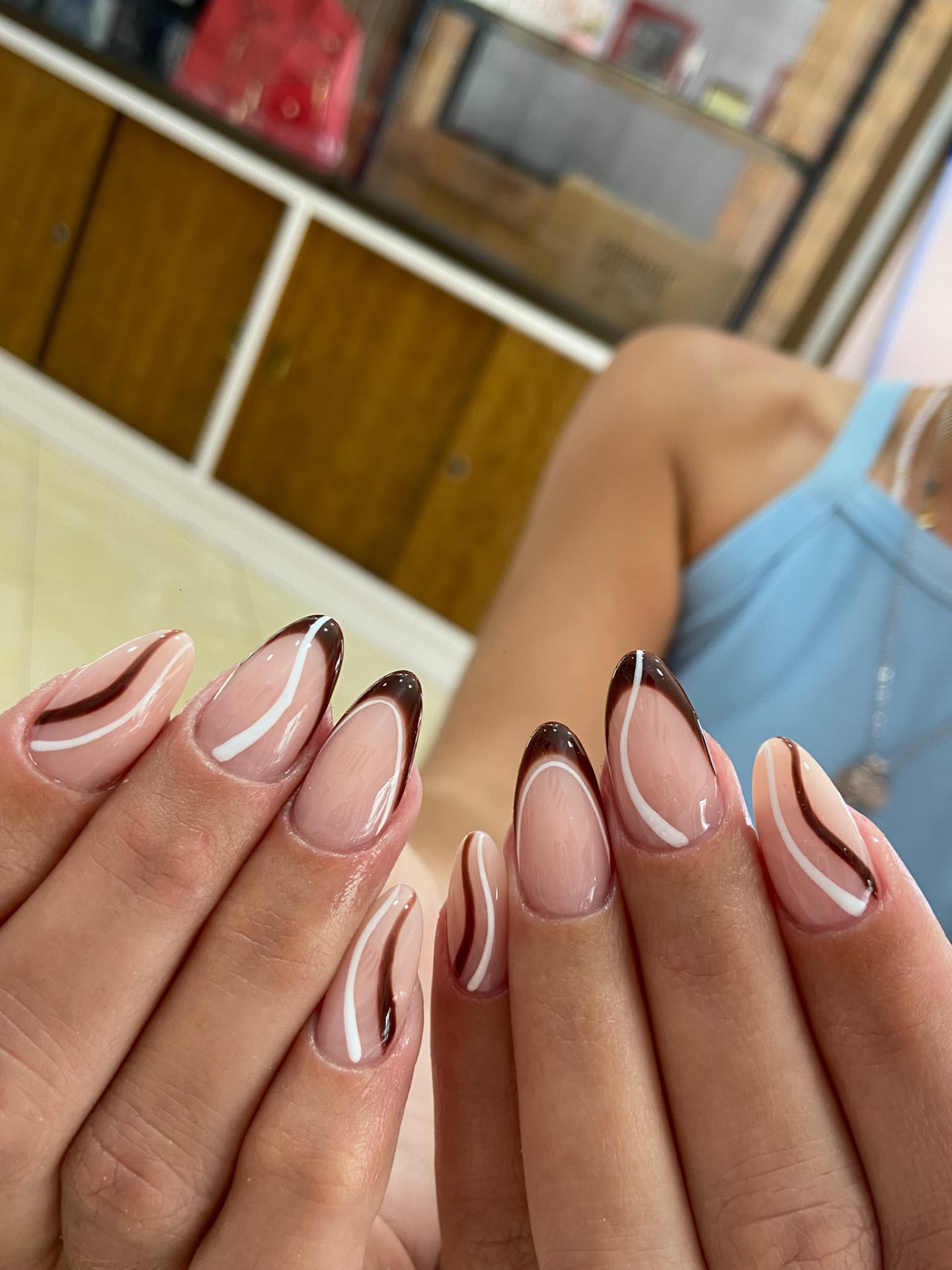 Manicura almendrada con líneas marrones y blancas