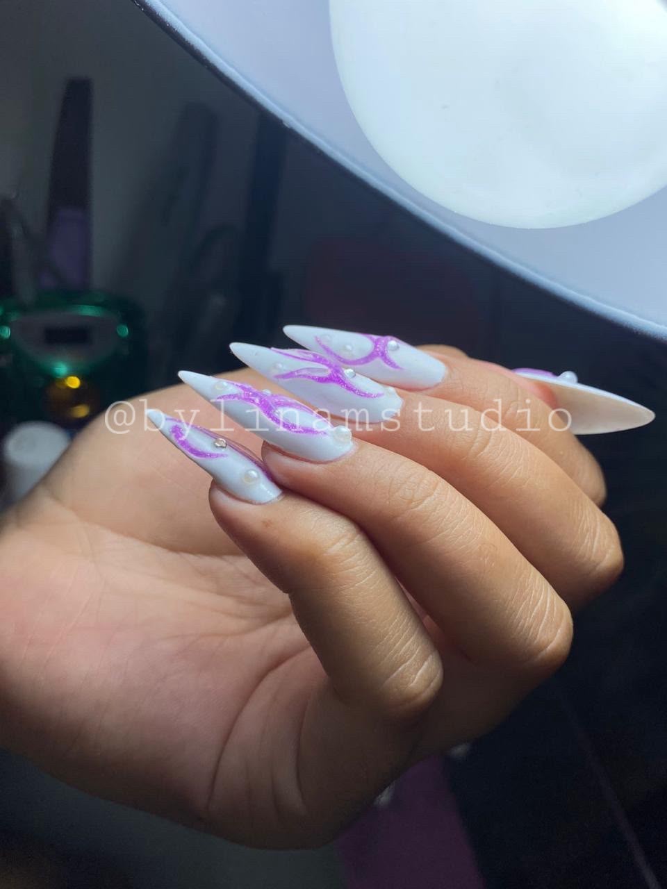 Manicura stiletto larga en blanco con llamas moradas purpurina y medias perlas